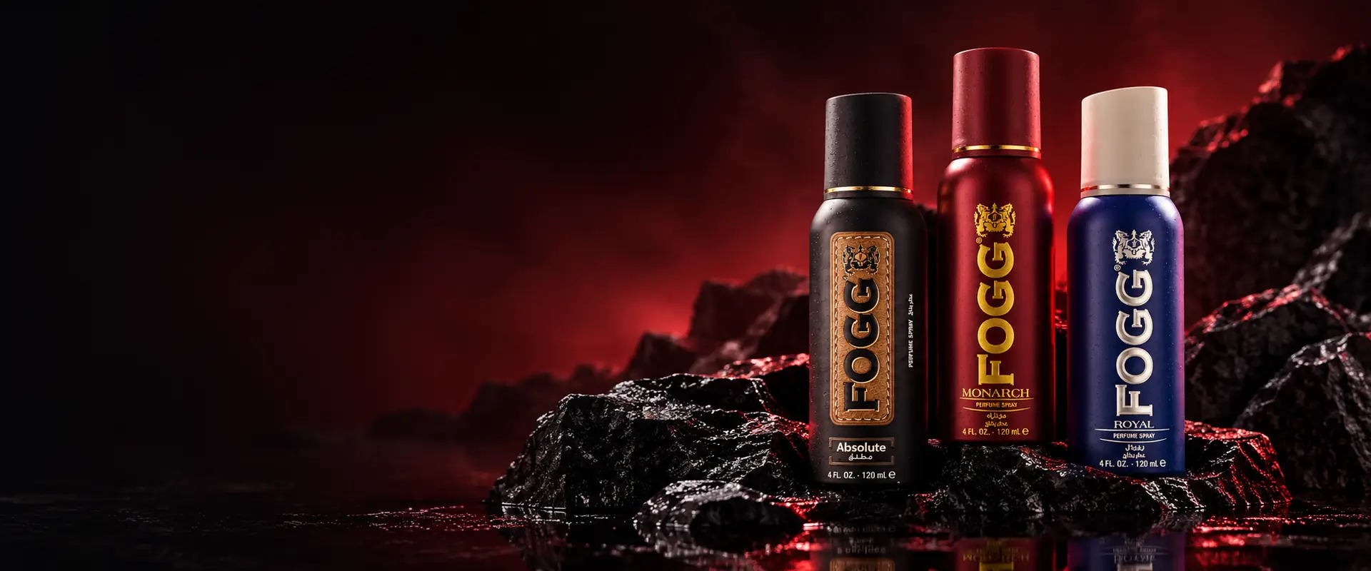 Les flacons FOGG ABSOLUTE, MONARCH et ROYAL posés sur des roches sombres, dans une lumière rouge.
